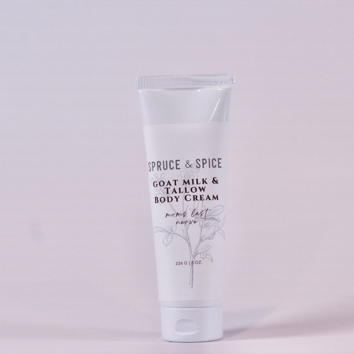 Body cream tube labeled 'Spruce & Spice' on a light gray background